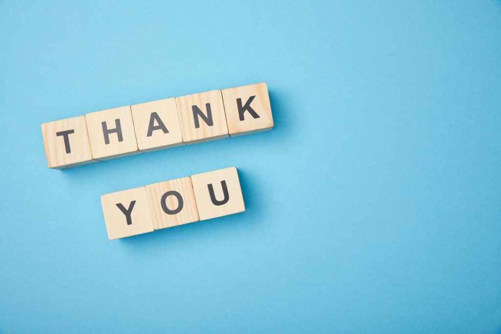 Holzwürfel mit den Worten „Thank you“ auf blauem Hintergrund